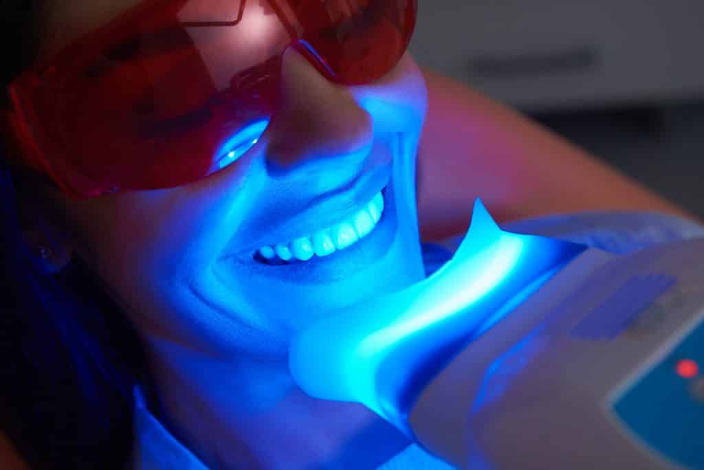 Adult woman is doing teeth whitening procedure