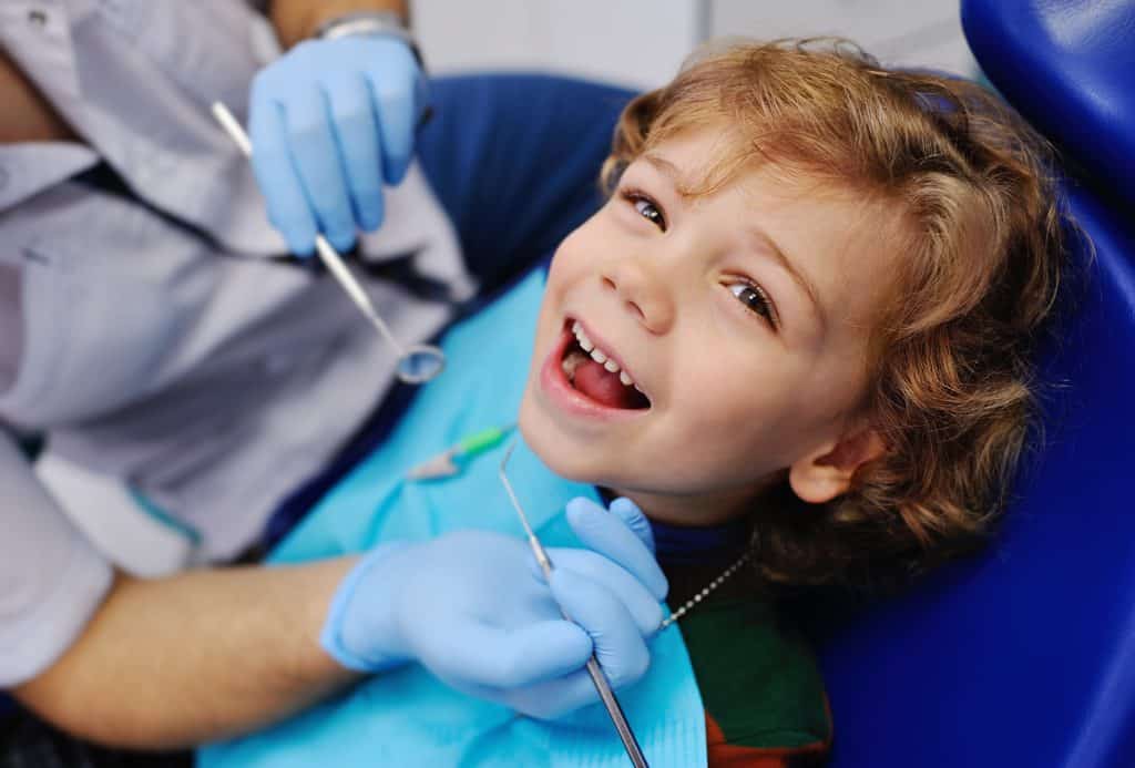 Smiling,Child,Sitting,In,A,Blue,Chair,Dental